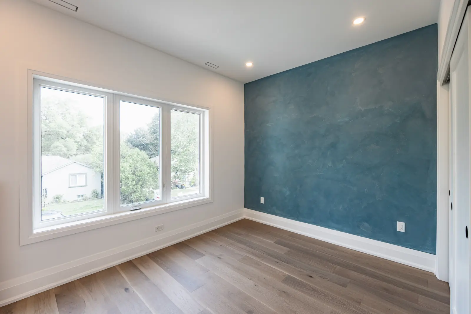 Room in a North York detached house renovation, with pale oak floors, white walls, and marble or warm wood millwork.