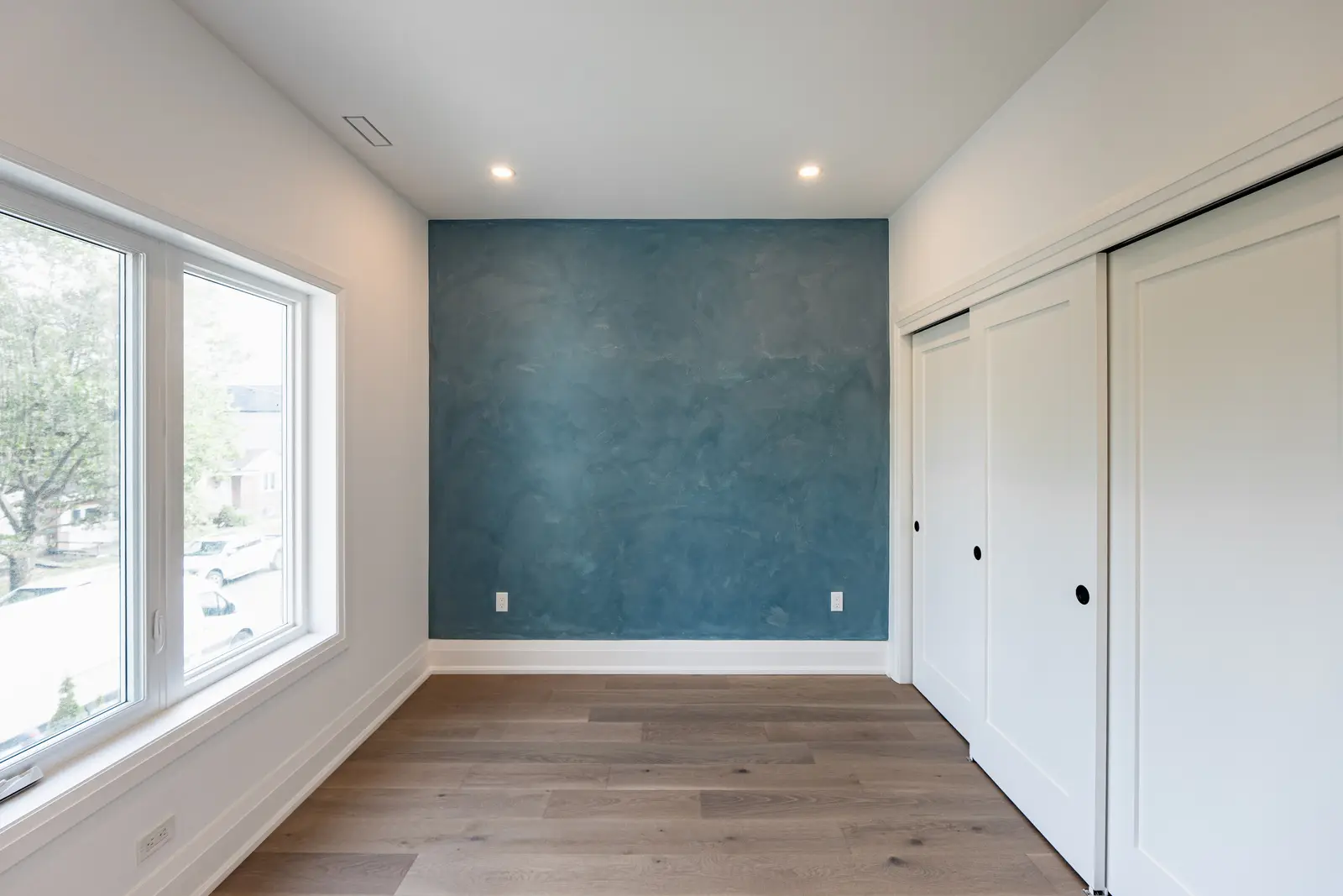 Room in a North York detached house renovation, with pale oak floors, white walls, and marble or warm wood millwork.