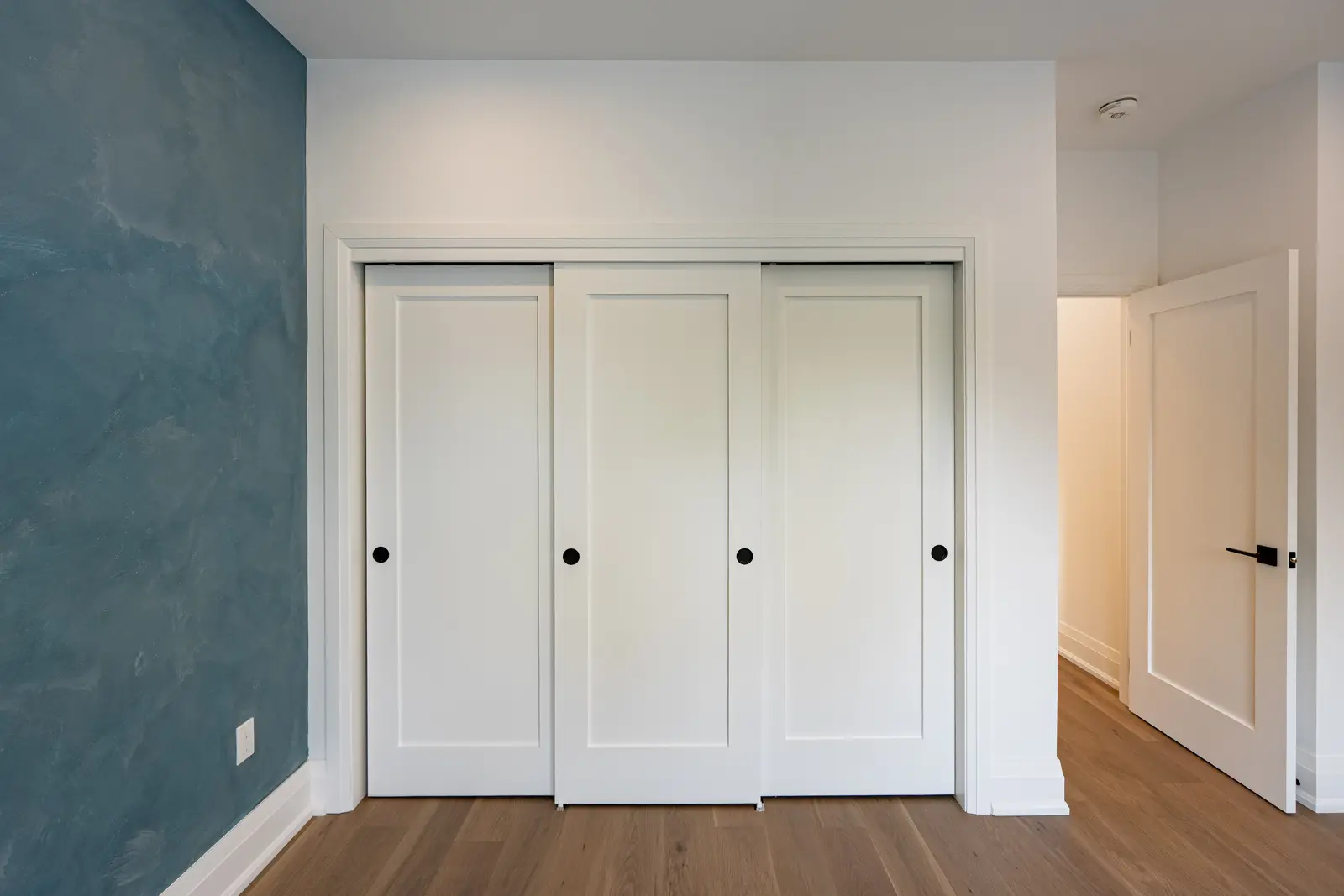 Room in a North York detached house renovation, with pale oak floors, white walls, and marble or warm wood millwork.
