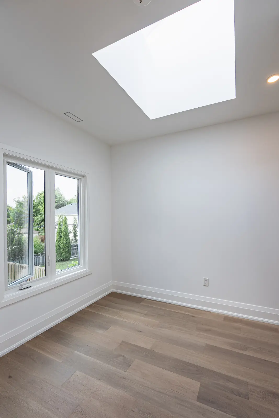 Room in a North York detached house renovation, with pale oak floors, white walls, and marble or warm wood millwork.