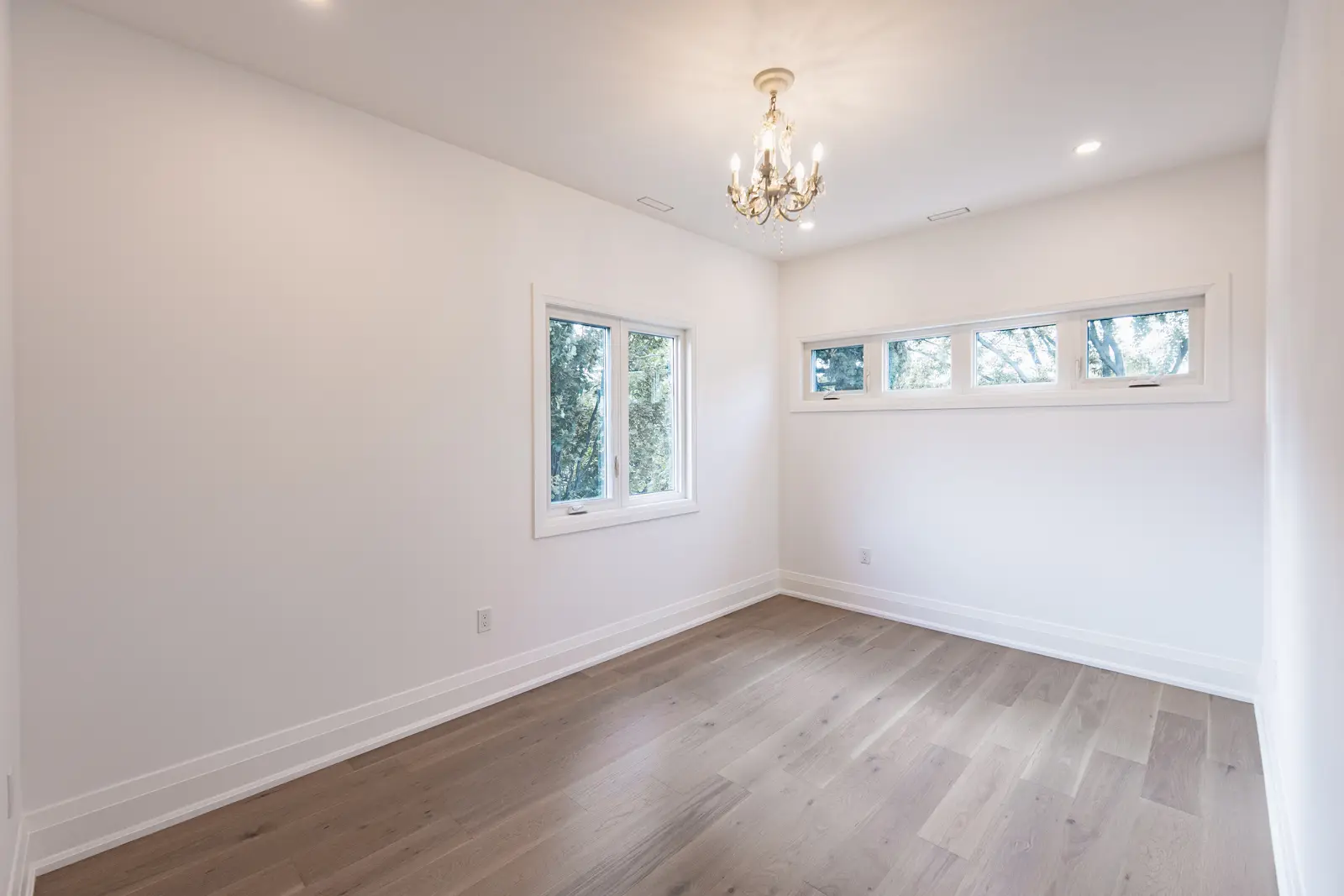 Room in a North York detached house renovation, with pale oak floors, white walls, and marble or warm wood millwork.