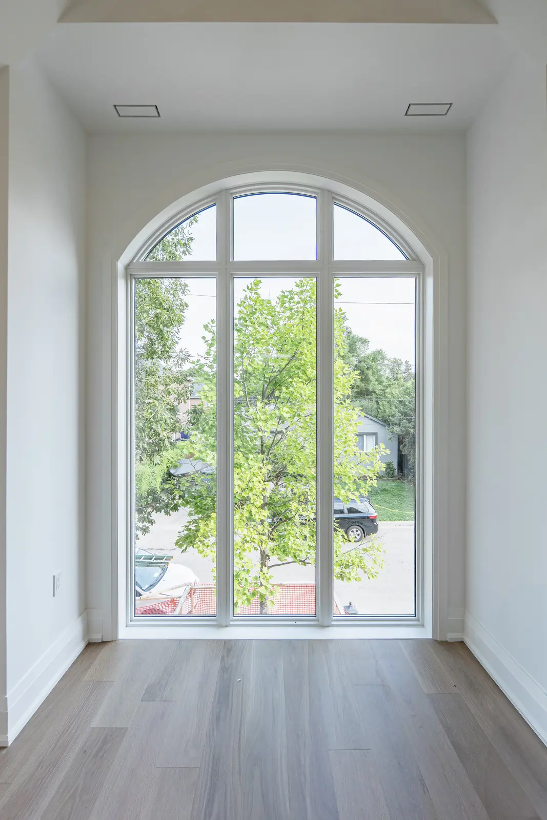 Room in a North York detached house renovation, with pale oak floors, white walls, and marble or warm wood millwork.