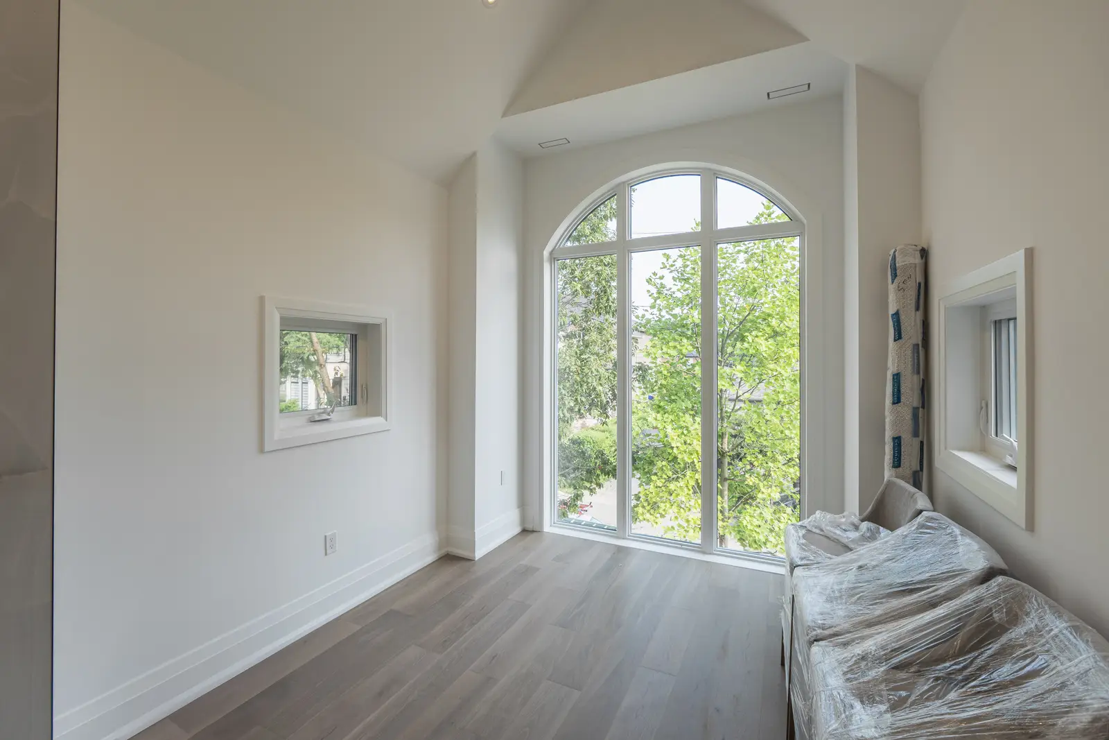 Room in a North York detached house renovation, with pale oak floors, white walls, and marble or warm wood millwork.