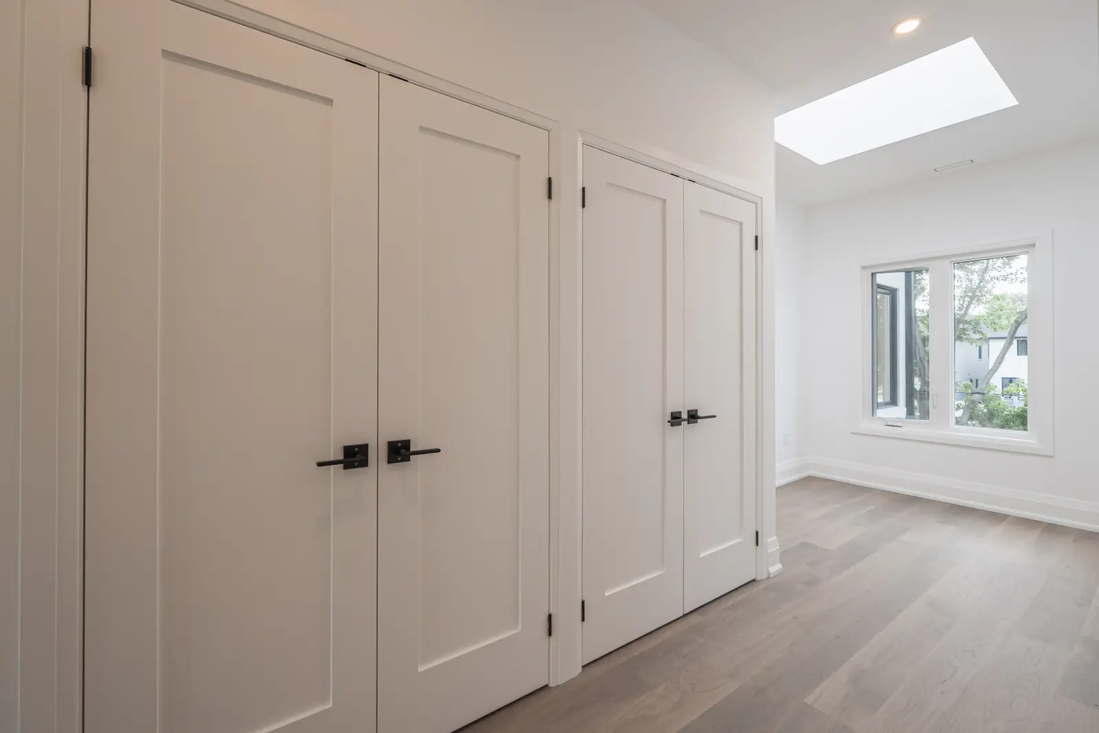 Room in a North York detached house renovation, with pale oak floors, white walls, and marble or warm wood millwork.