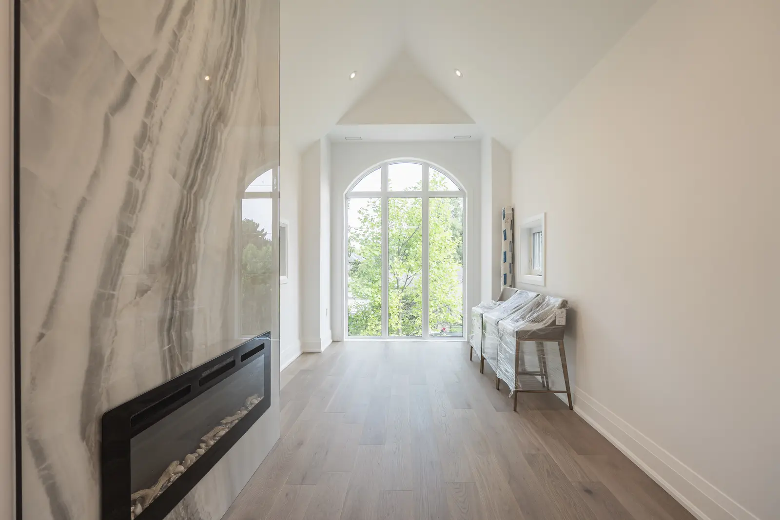 Room in a North York detached house renovation, with pale oak floors, white walls, and marble or warm wood millwork.