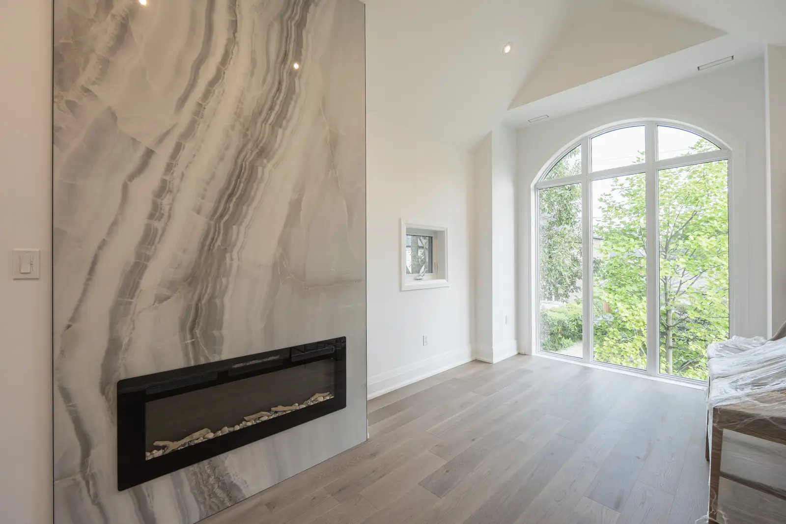 Room in a North York detached house renovation, with pale oak floors, white walls, and marble or warm wood millwork.