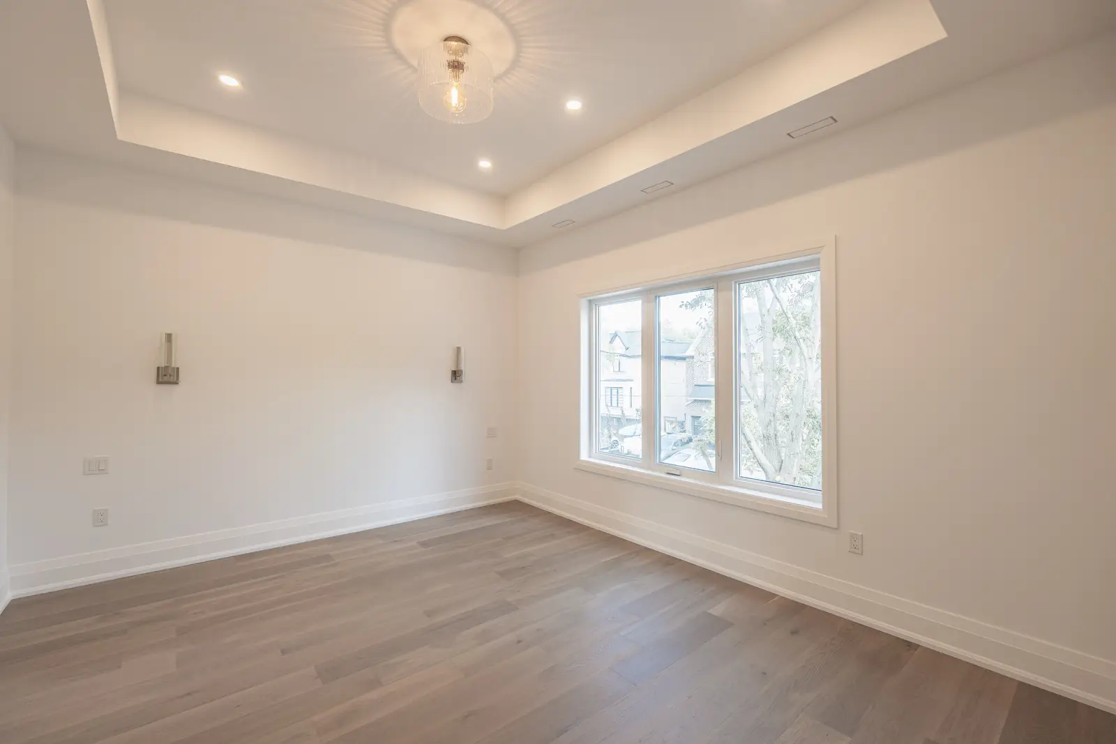 Room in a North York detached house renovation, with pale oak floors, white walls, and marble or warm wood millwork.