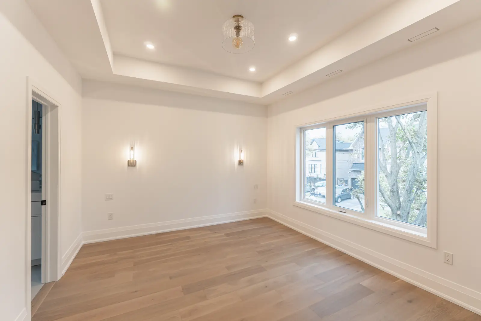 Room in a North York detached house renovation, with pale oak floors, white walls, and marble or warm wood millwork.