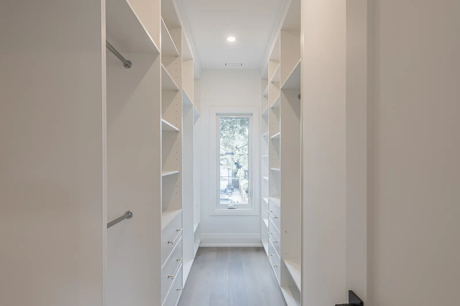 Room in a North York detached house renovation, with pale oak floors, white walls, and marble or warm wood millwork.