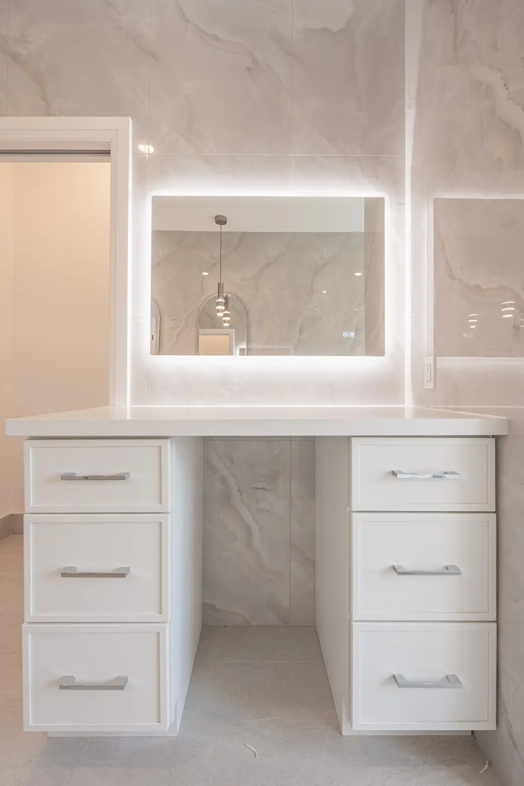Room in a North York detached house renovation, with pale oak floors, white walls, and marble or warm wood millwork.