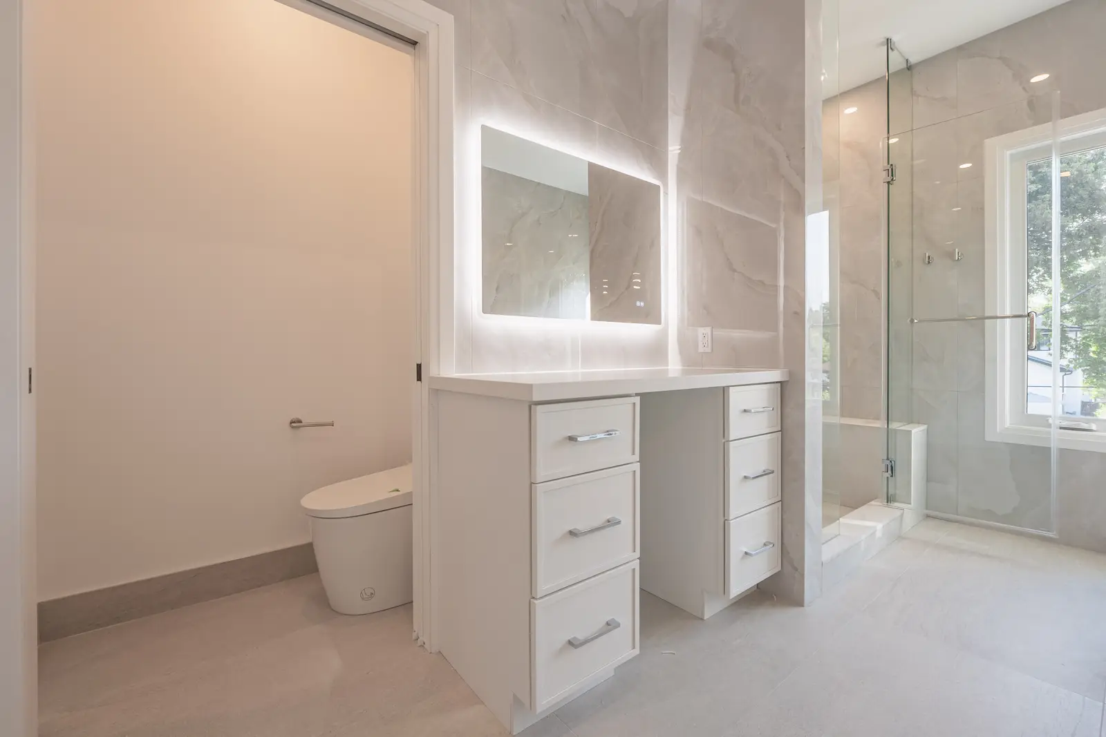 Room in a North York detached house renovation, with pale oak floors, white walls, and marble or warm wood millwork.