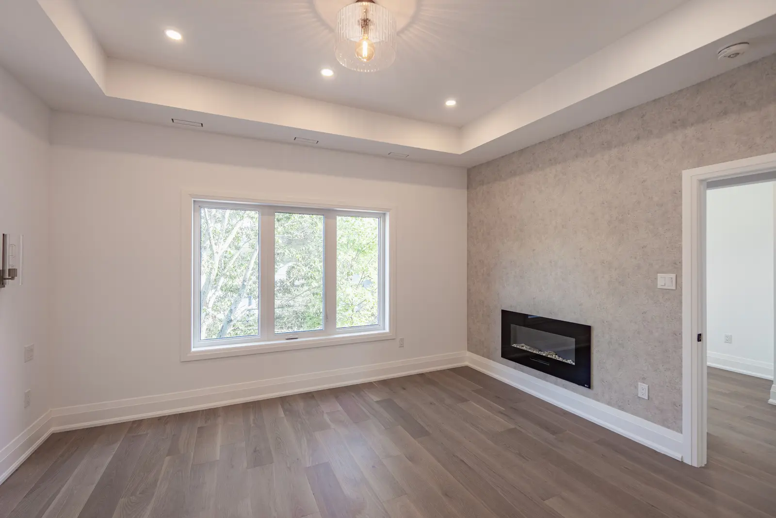 Room in a North York detached house renovation, with pale oak floors, white walls, and marble or warm wood millwork.