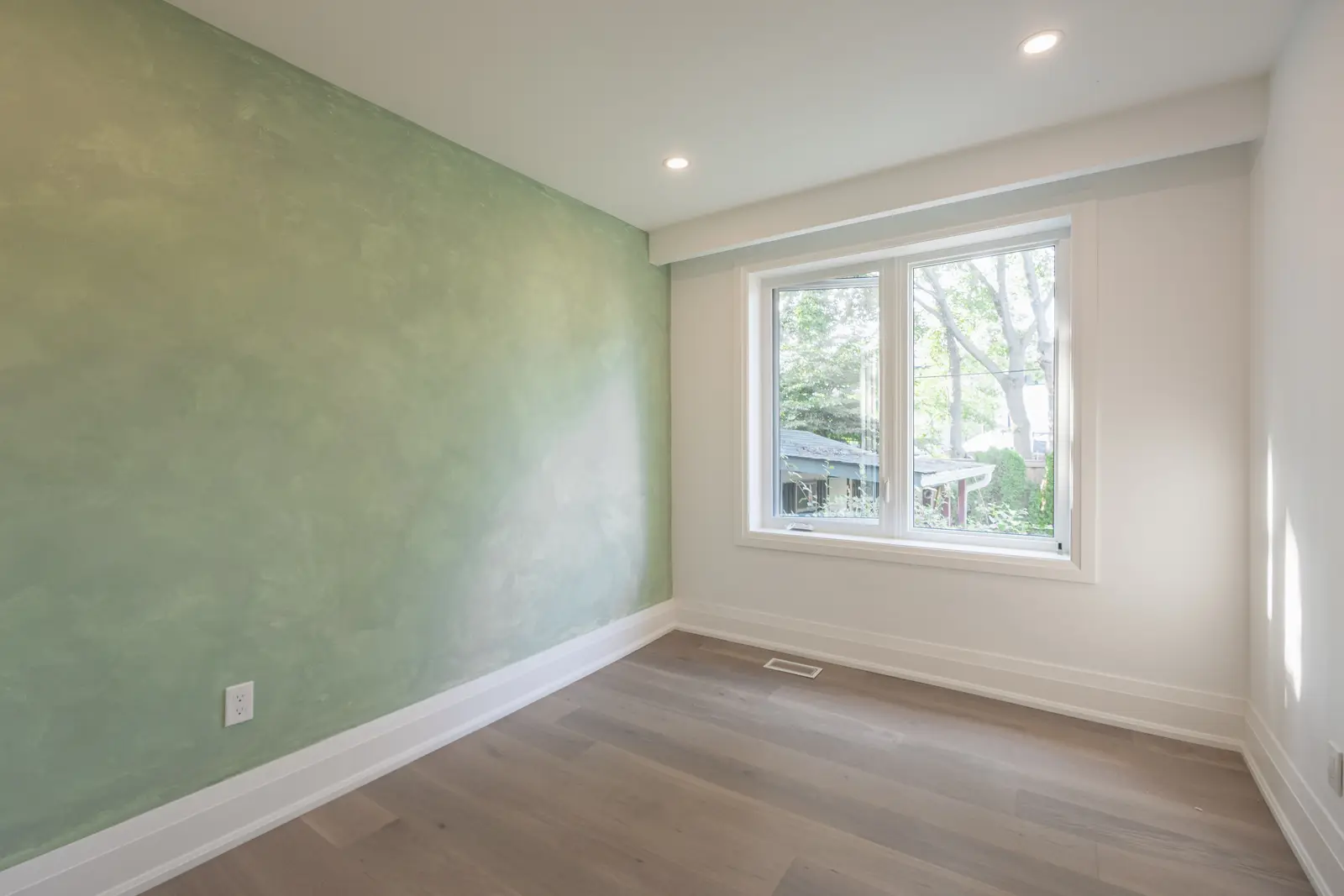 Room in a North York detached house renovation, with pale oak floors, white walls, and marble or warm wood millwork.