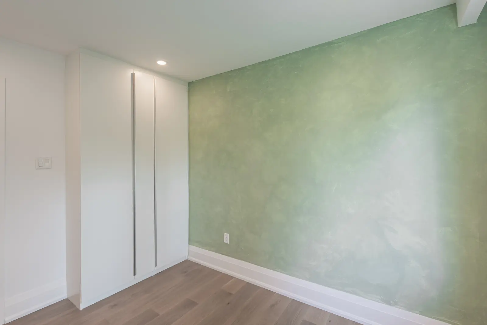 Room in a North York detached house renovation, with pale oak floors, white walls, and marble or warm wood millwork.