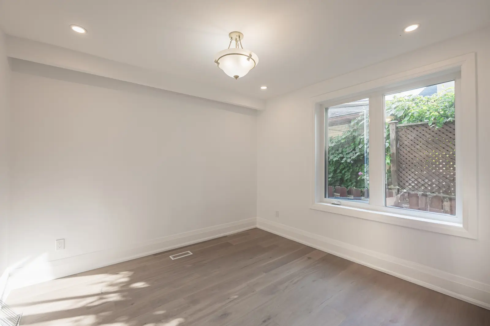 Room in a North York detached house renovation, with pale oak floors, white walls, and marble or warm wood millwork.