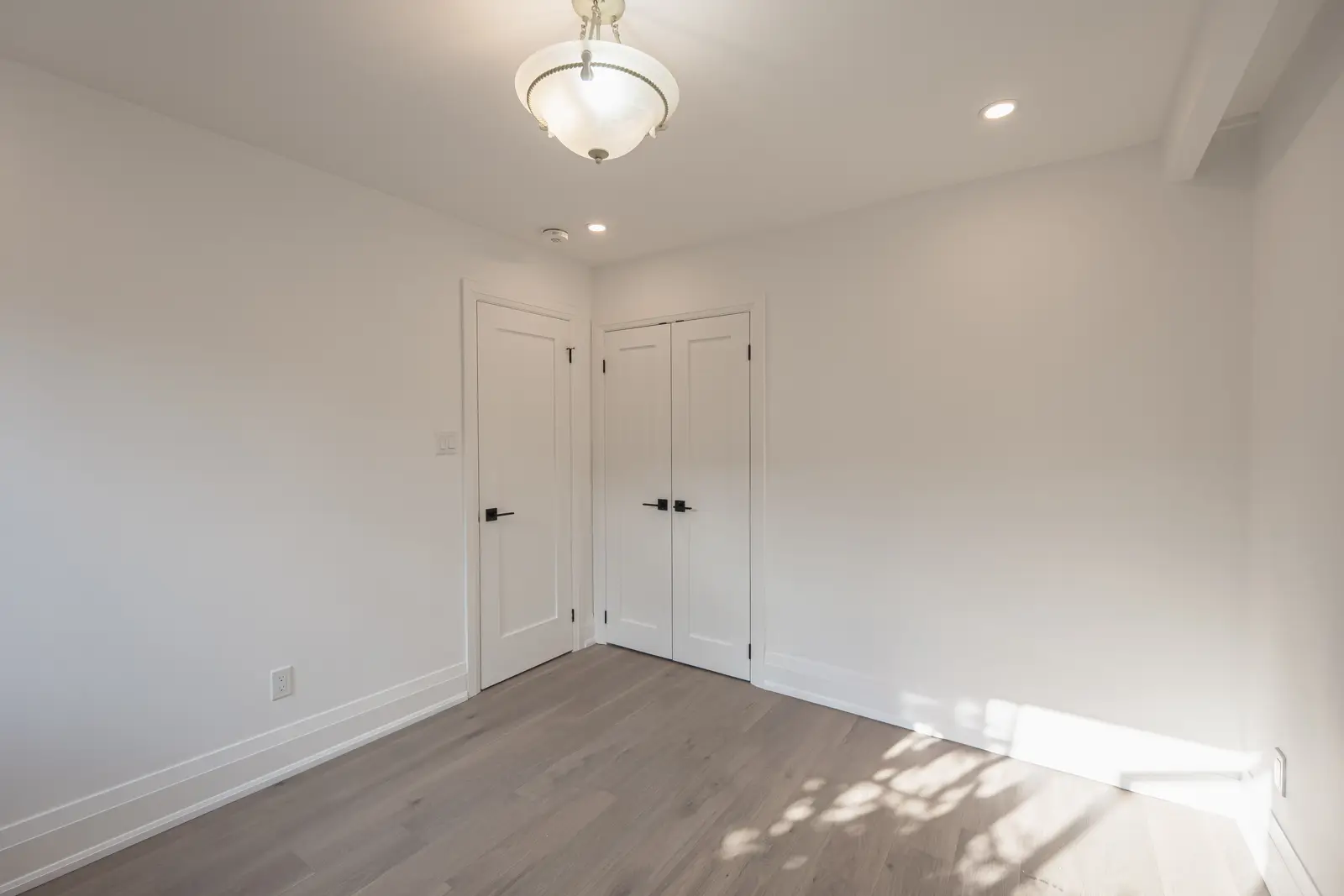 Room in a North York detached house renovation, with pale oak floors, white walls, and marble or warm wood millwork.