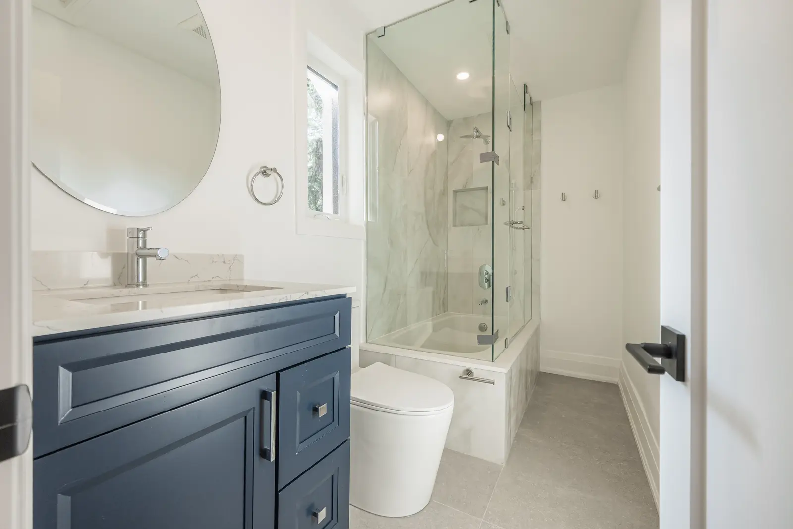 Room in a North York detached house renovation, with pale oak floors, white walls, and marble or warm wood millwork.
