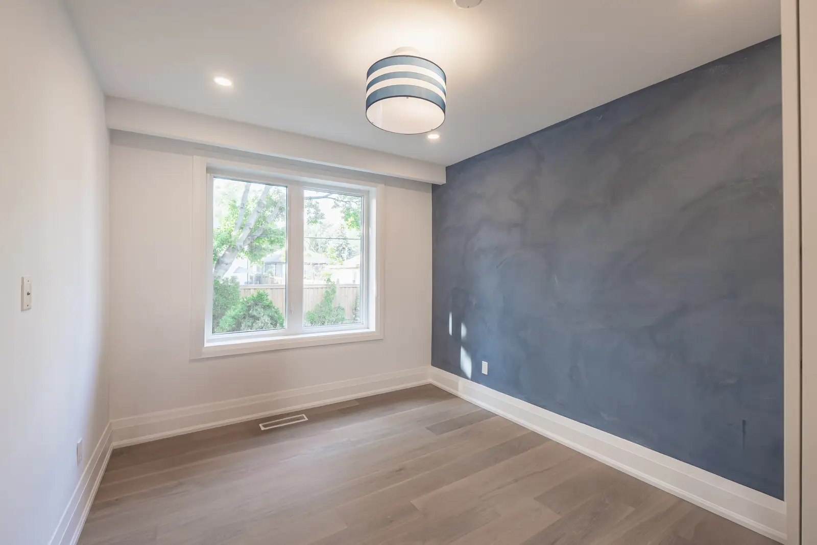 Room in a North York detached house renovation, with pale oak floors, white walls, and marble or warm wood millwork.