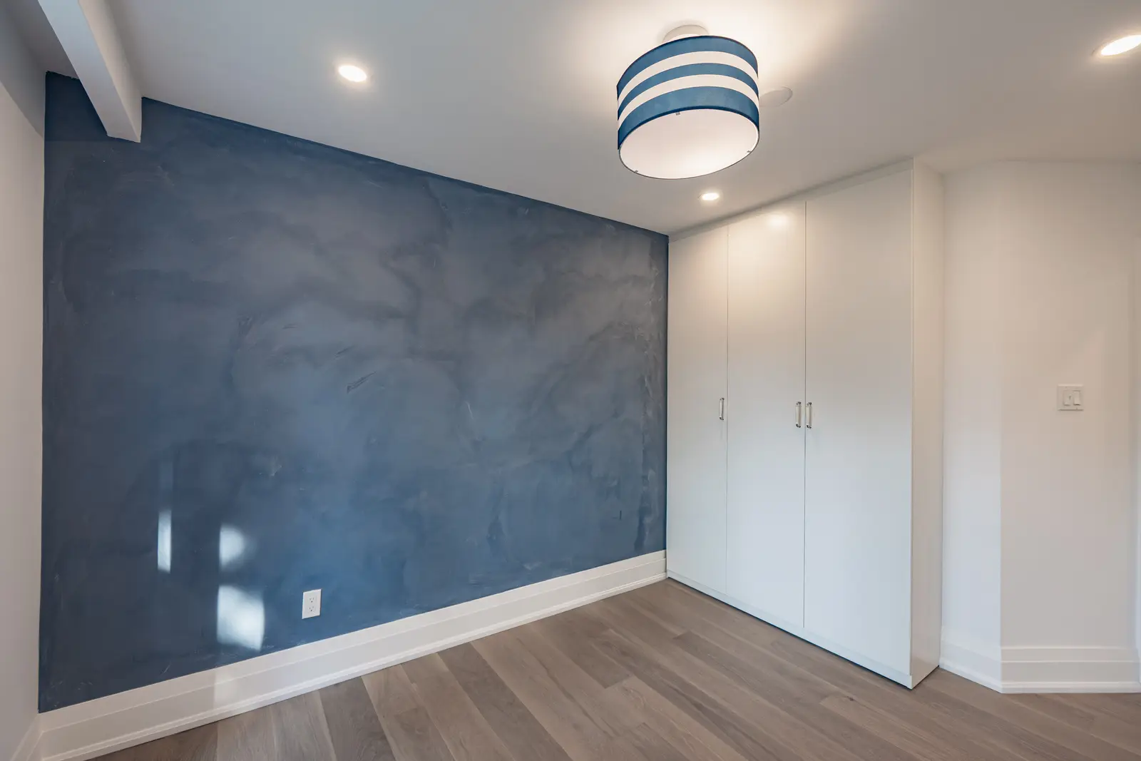 Room in a North York detached house renovation, with pale oak floors, white walls, and marble or warm wood millwork.