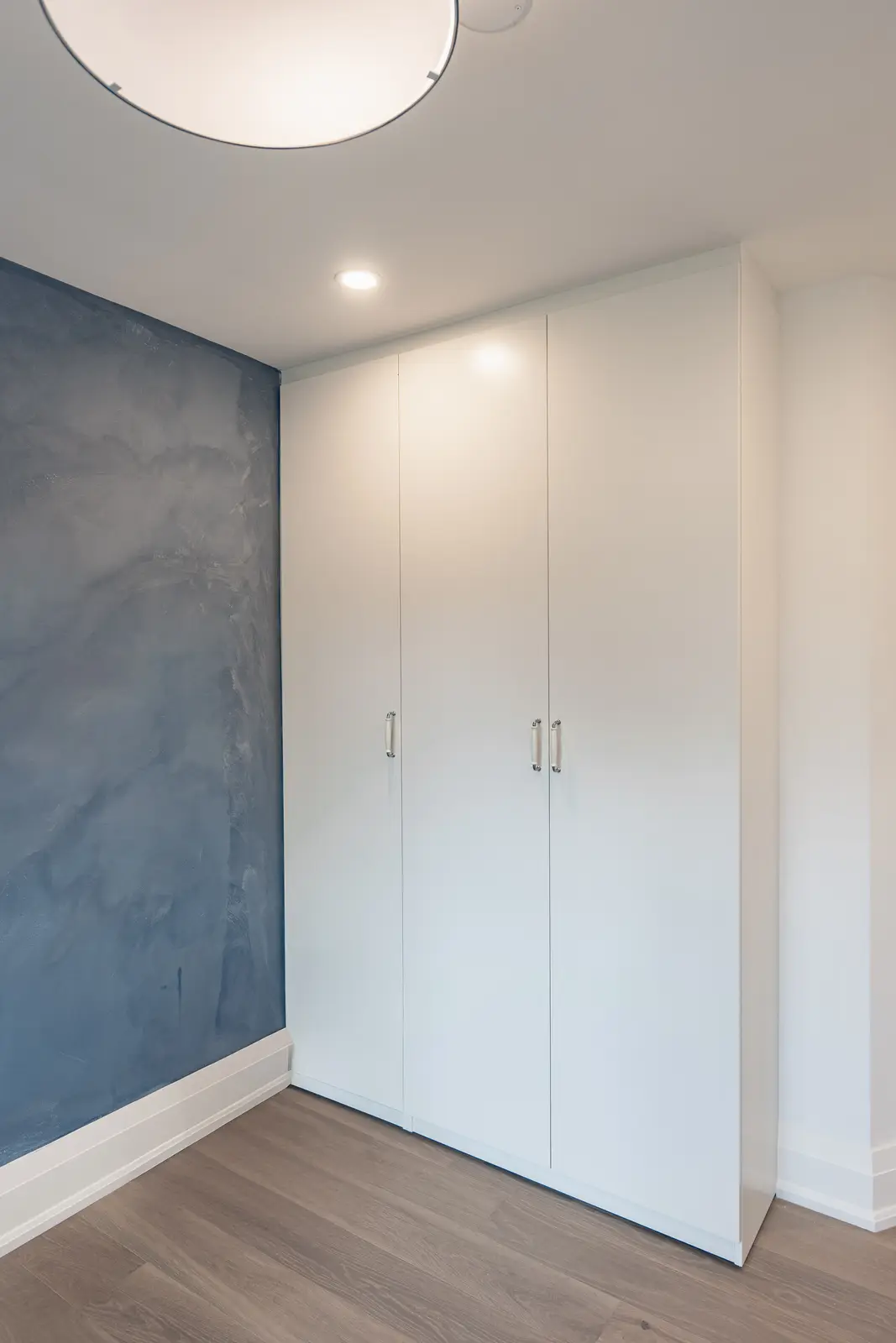 Room in a North York detached house renovation, with pale oak floors, white walls, and marble or warm wood millwork.