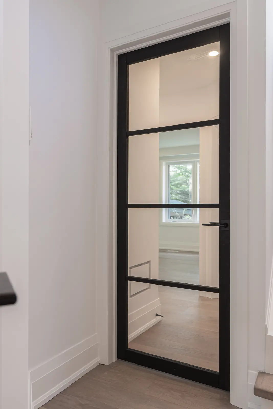 Room in a North York detached house renovation, with pale oak floors, white walls, and marble or warm wood millwork.