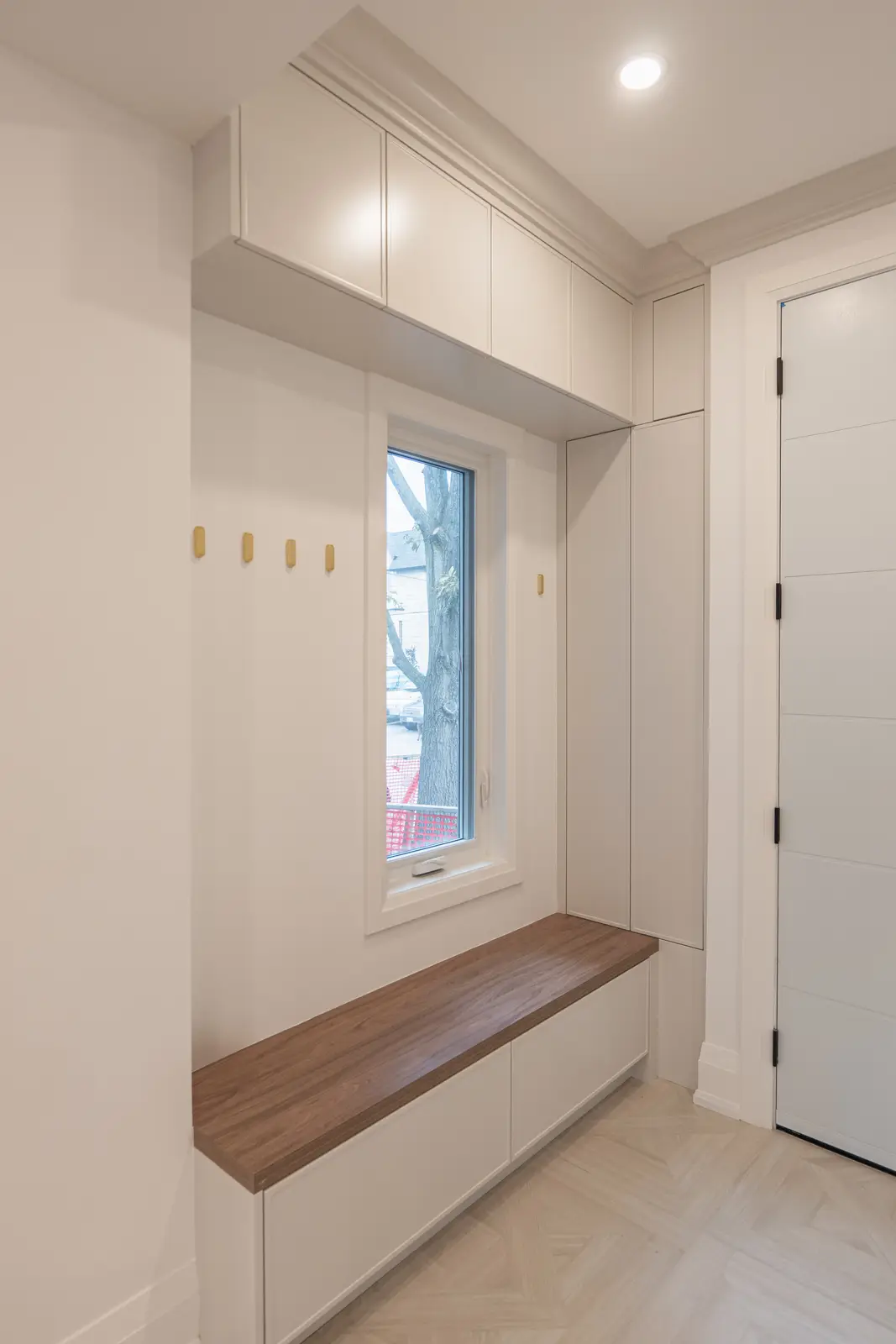 Room in a North York detached house renovation, with pale oak floors, white walls, and marble or warm wood millwork.