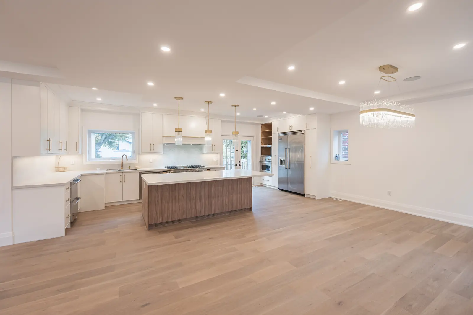 Room in a North York detached house renovation, with pale oak floors, white walls, and marble or warm wood millwork.
