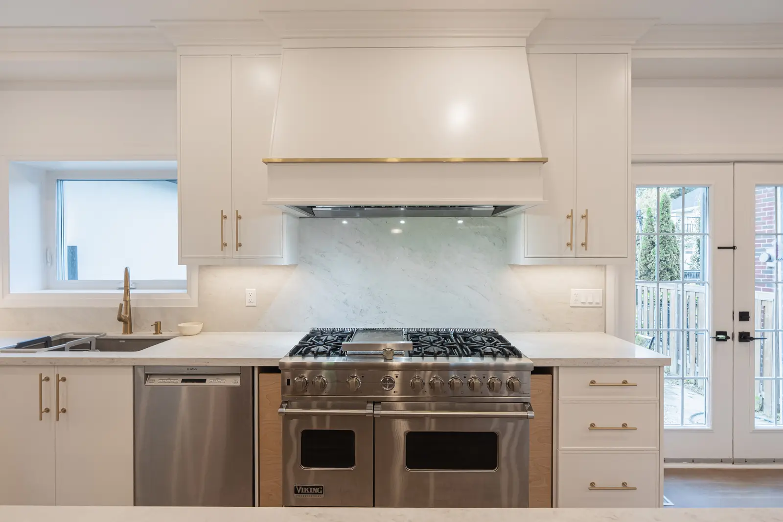 Room in a North York detached house renovation, with pale oak floors, white walls, and marble or warm wood millwork.