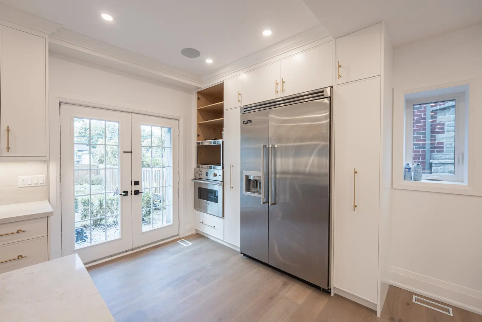 Room in a North York detached house renovation, with pale oak floors, white walls, and marble or warm wood millwork.