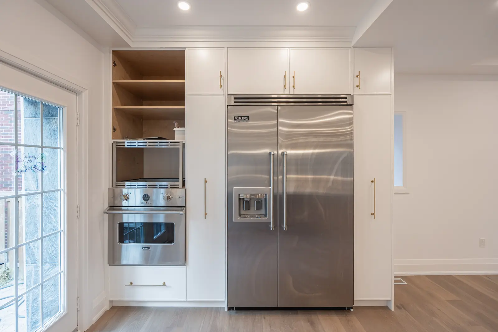 Room in a North York detached house renovation, with pale oak floors, white walls, and marble or warm wood millwork.