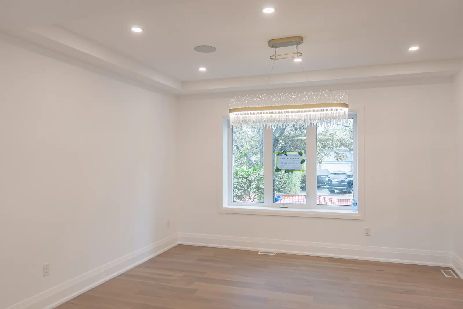 Room in a North York detached house renovation, with pale oak floors, white walls, and marble or warm wood millwork.