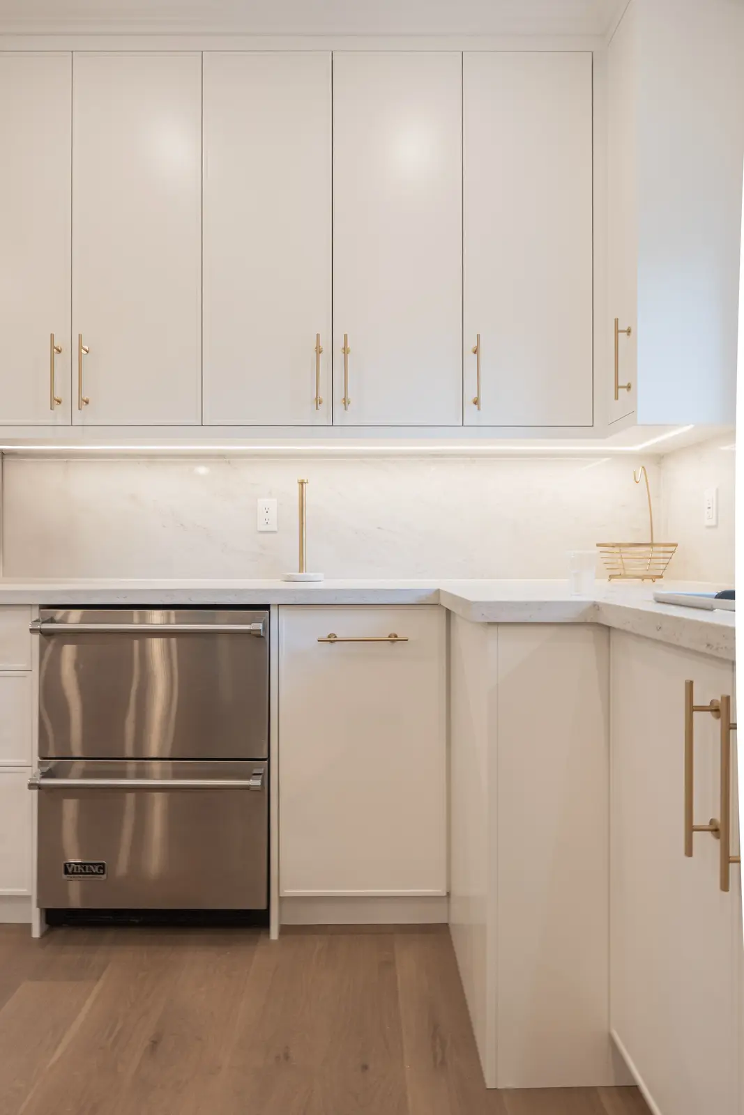 Room in a North York detached house renovation, with pale oak floors, white walls, and marble or warm wood millwork.