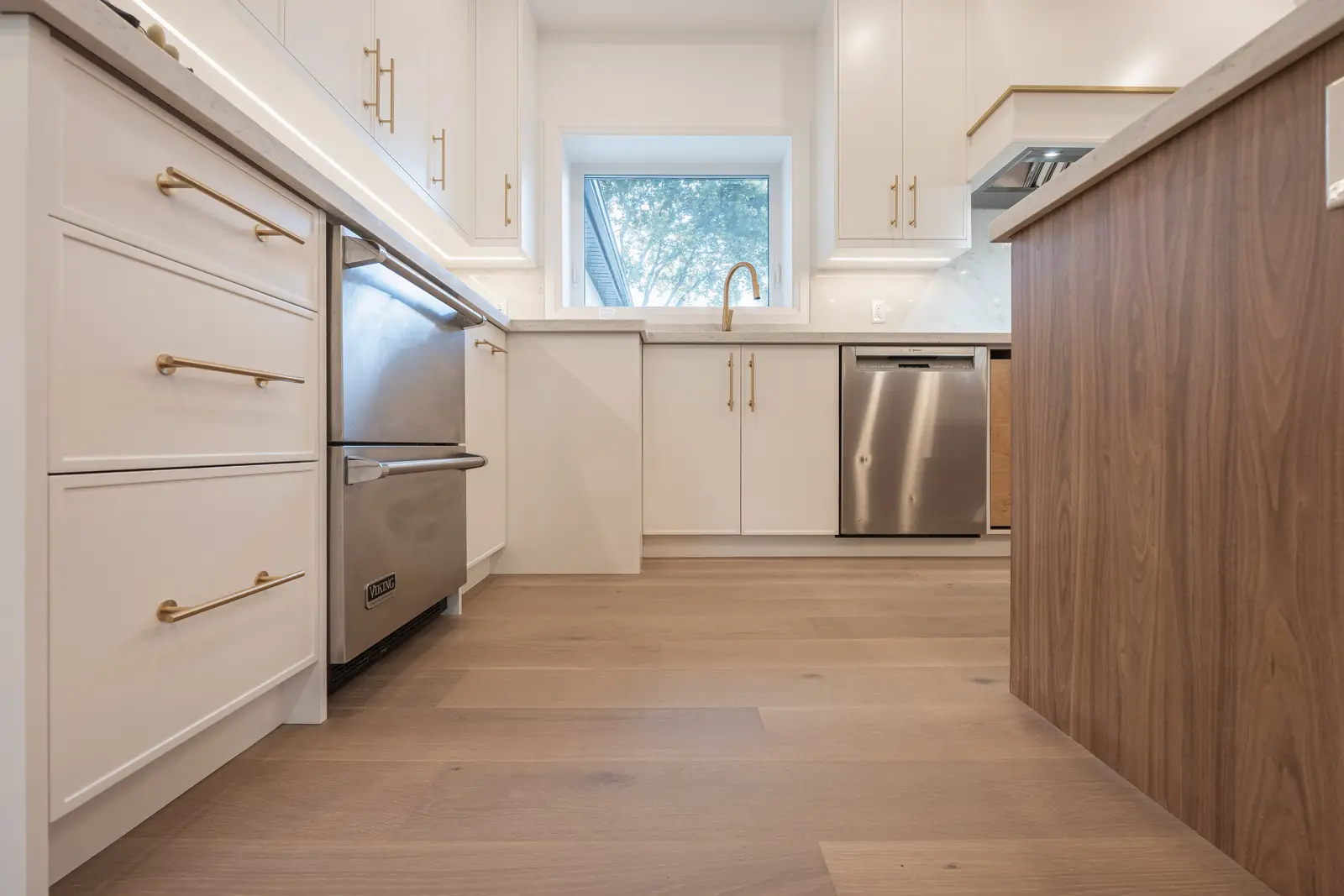 Room in a North York detached house renovation, with pale oak floors, white walls, and marble or warm wood millwork.