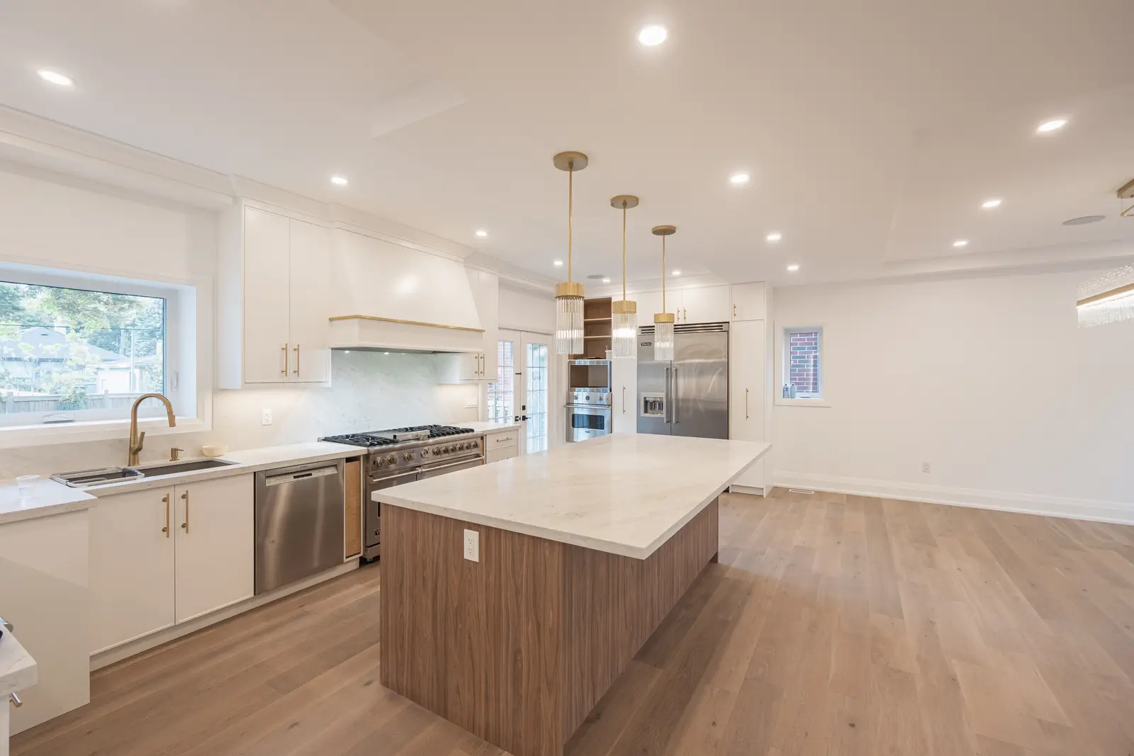 Room in a North York detached house renovation, with pale oak floors, white walls, and marble or warm wood millwork.