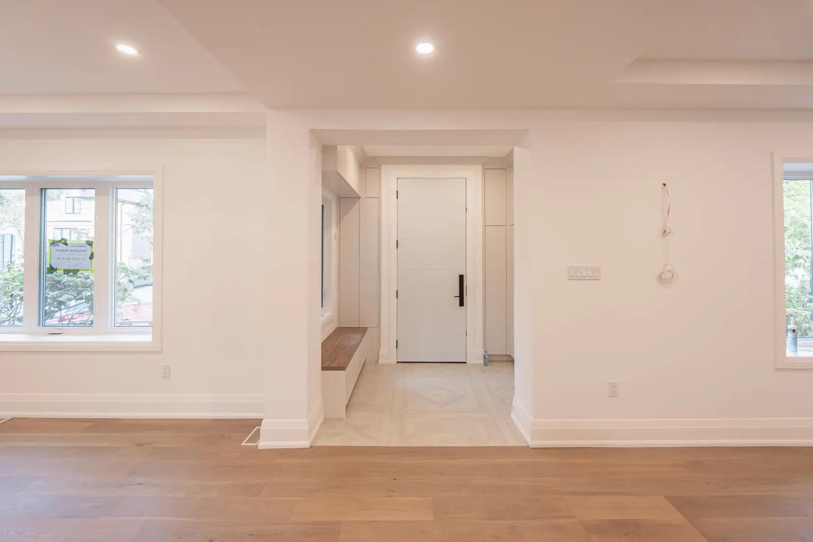 Room in a North York detached house renovation, with pale oak floors, white walls, and marble or warm wood millwork.