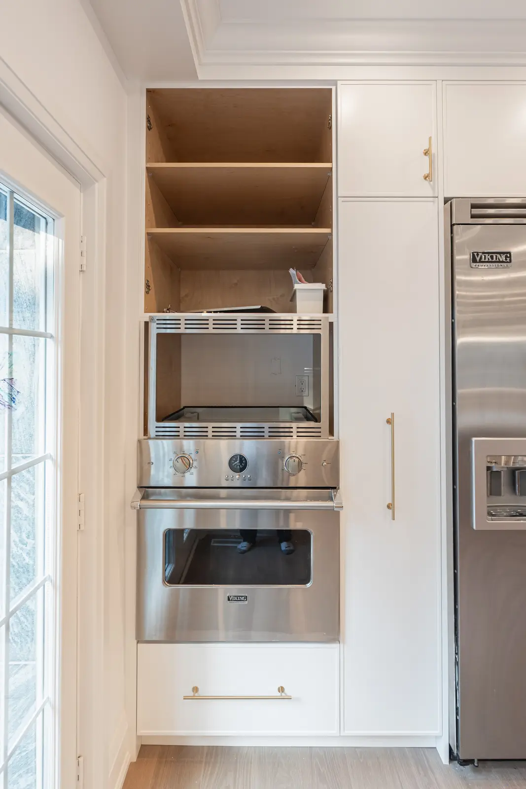 Room in a North York detached house renovation, with pale oak floors, white walls, and marble or warm wood millwork.