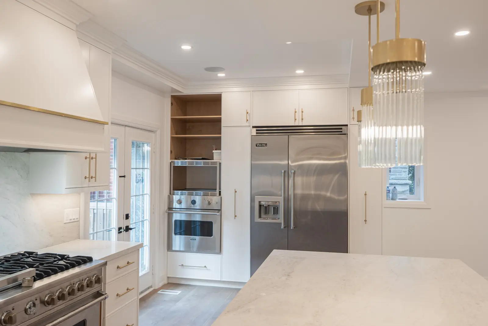 Room in a North York detached house renovation, with pale oak floors, white walls, and marble or warm wood millwork.