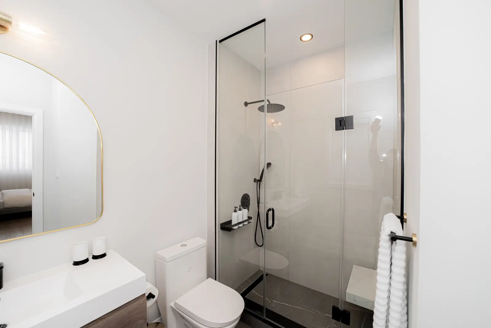Interior of a Thornhill detached house renovation, with pale wood floors, black furnishings, and a walnut vanity in the primary bathroom.