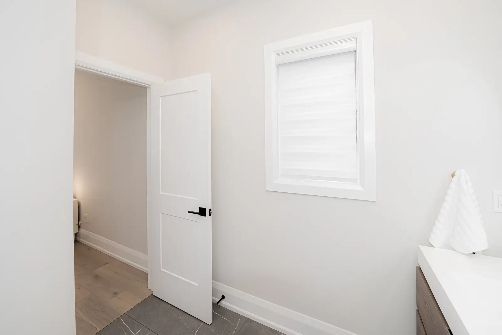 Interior of a Thornhill detached house renovation, with pale wood floors, black furnishings, and a walnut vanity in the primary bathroom.