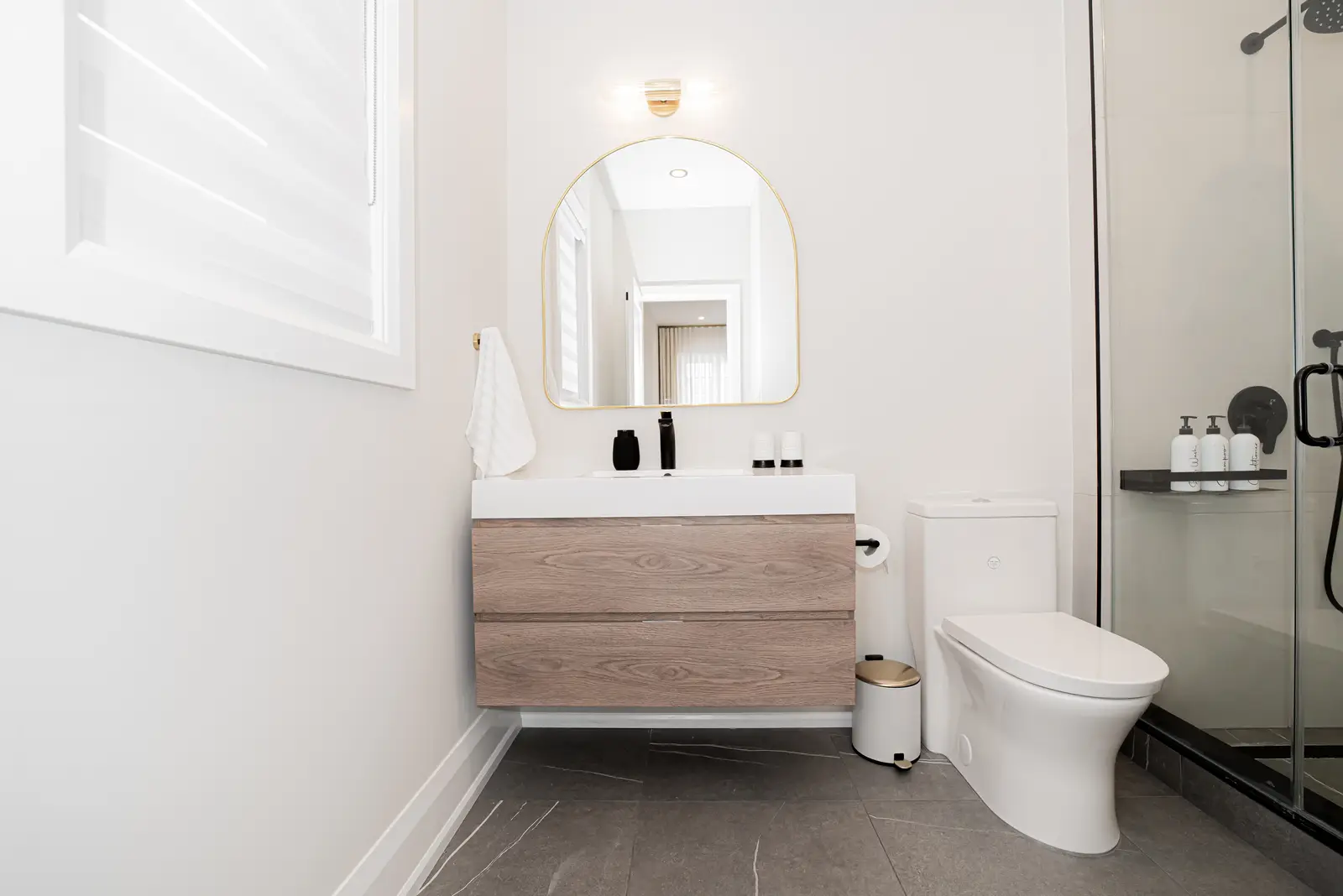 Interior of a Thornhill detached house renovation, with pale wood floors, black furnishings, and a walnut vanity in the primary bathroom.