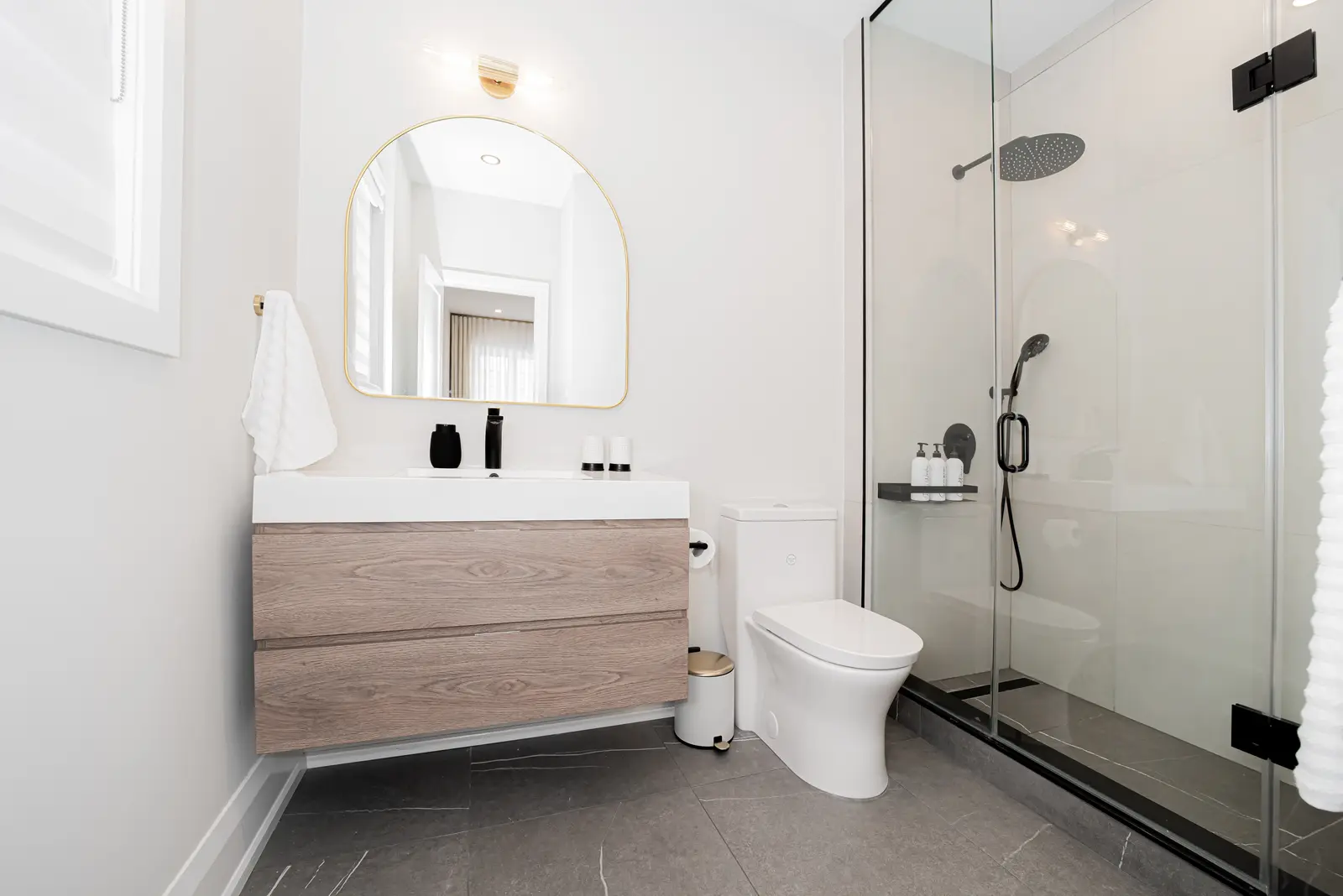 Interior of a Thornhill detached house renovation, with pale wood floors, black furnishings, and a walnut vanity in the primary bathroom.