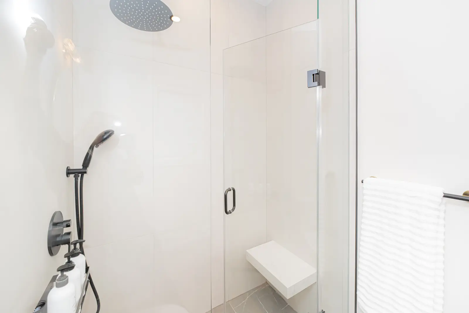 Interior of a Thornhill detached house renovation, with pale wood floors, black furnishings, and a walnut vanity in the primary bathroom.