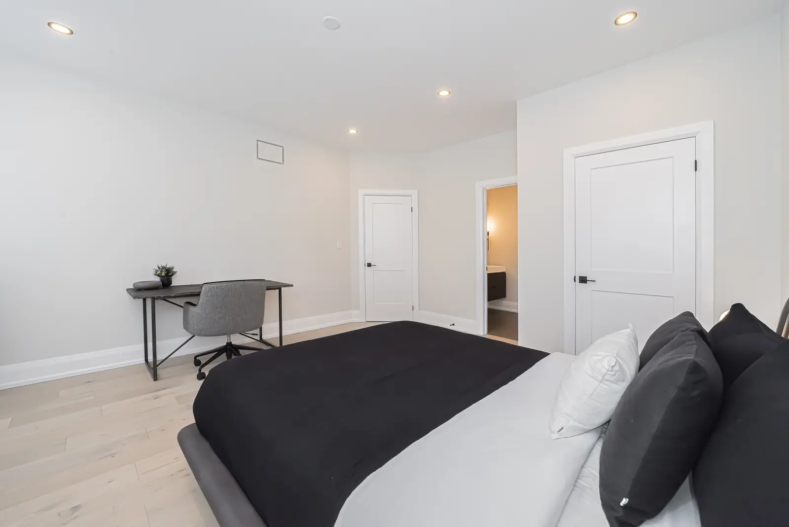 Interior of a Thornhill detached house renovation, with pale wood floors, black furnishings, and a walnut vanity in the primary bathroom.