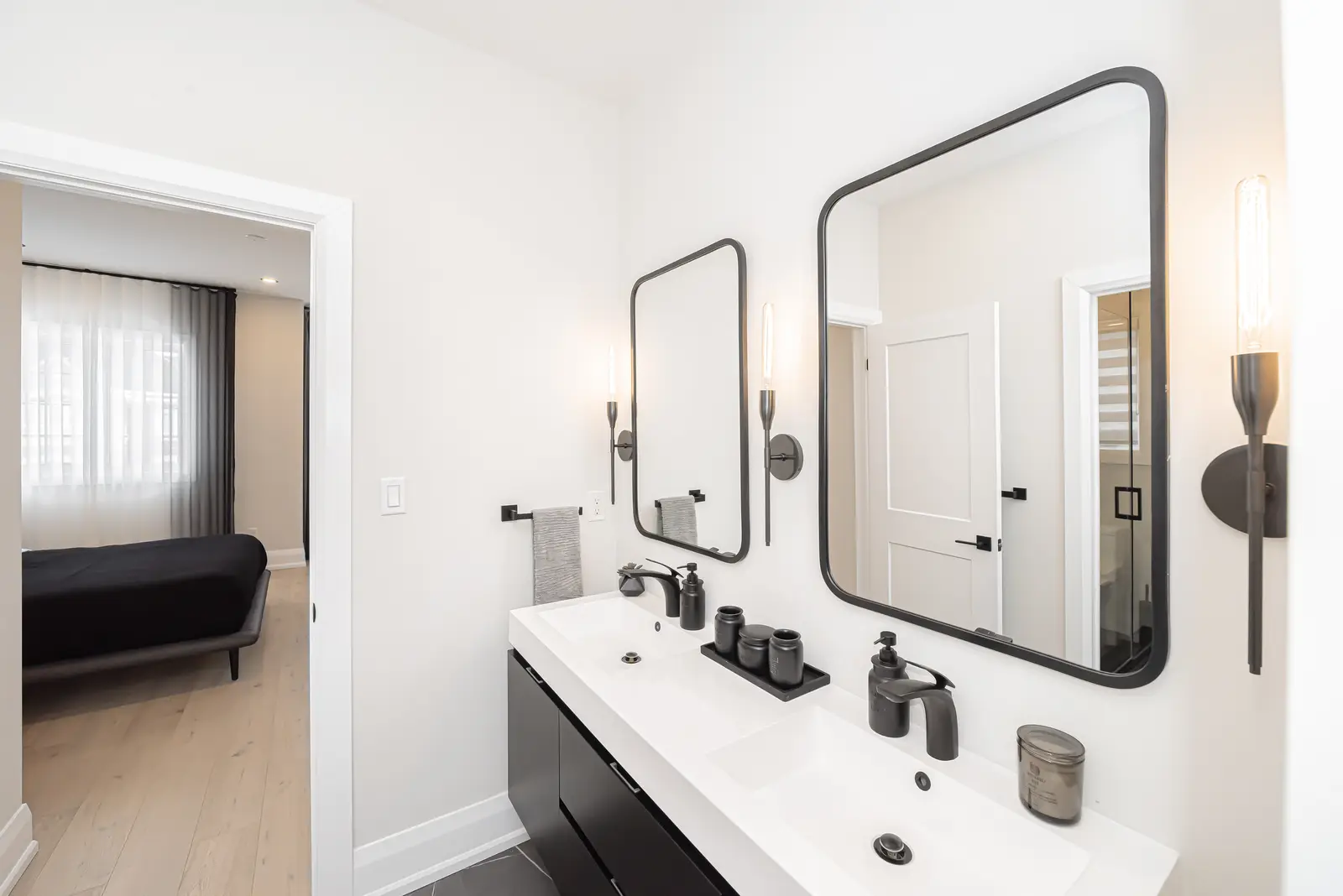 Interior of a Thornhill detached house renovation, with pale wood floors, black furnishings, and a walnut vanity in the primary bathroom.