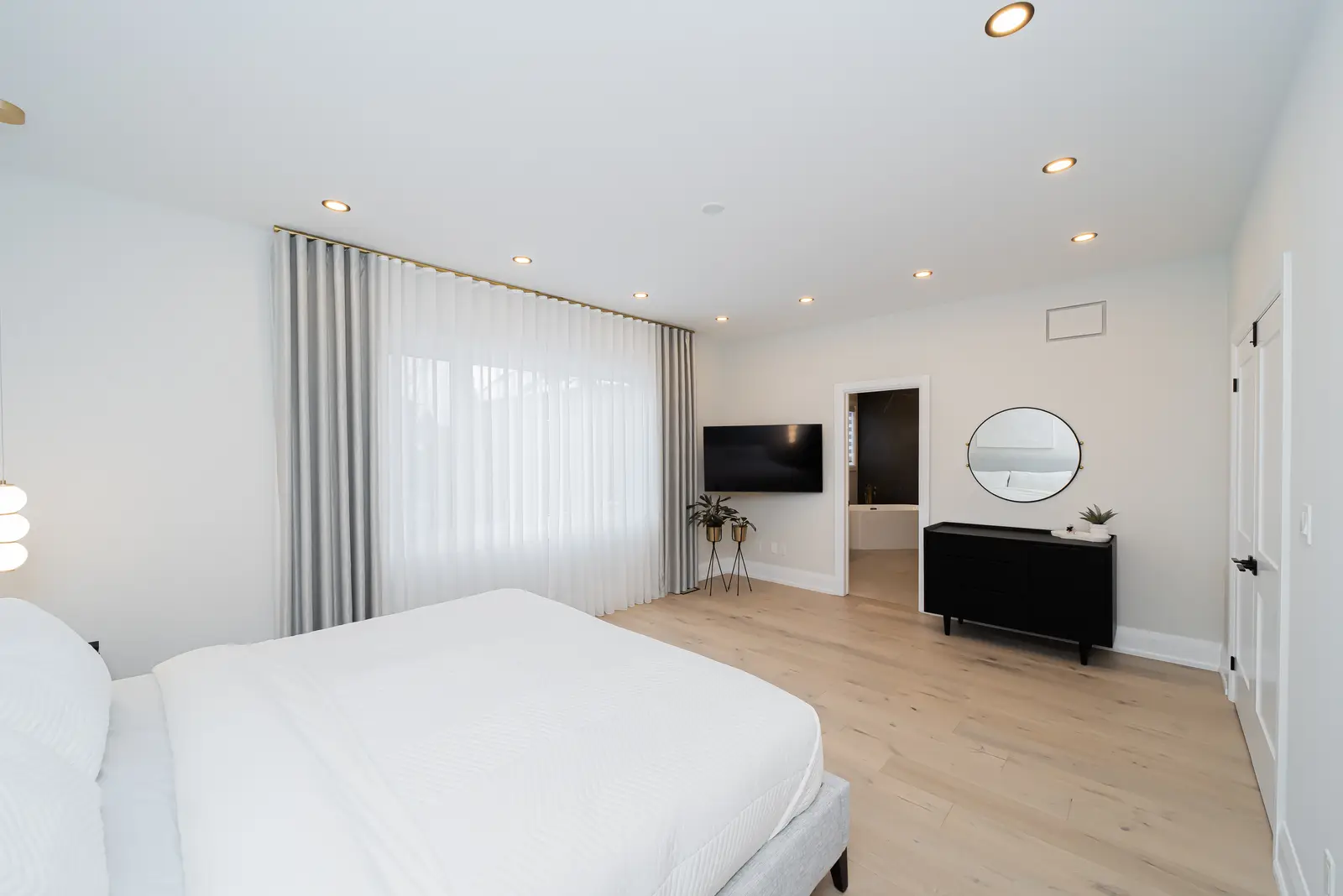 Interior of a Thornhill detached house renovation, with pale wood floors, black furnishings, and a walnut vanity in the primary bathroom.