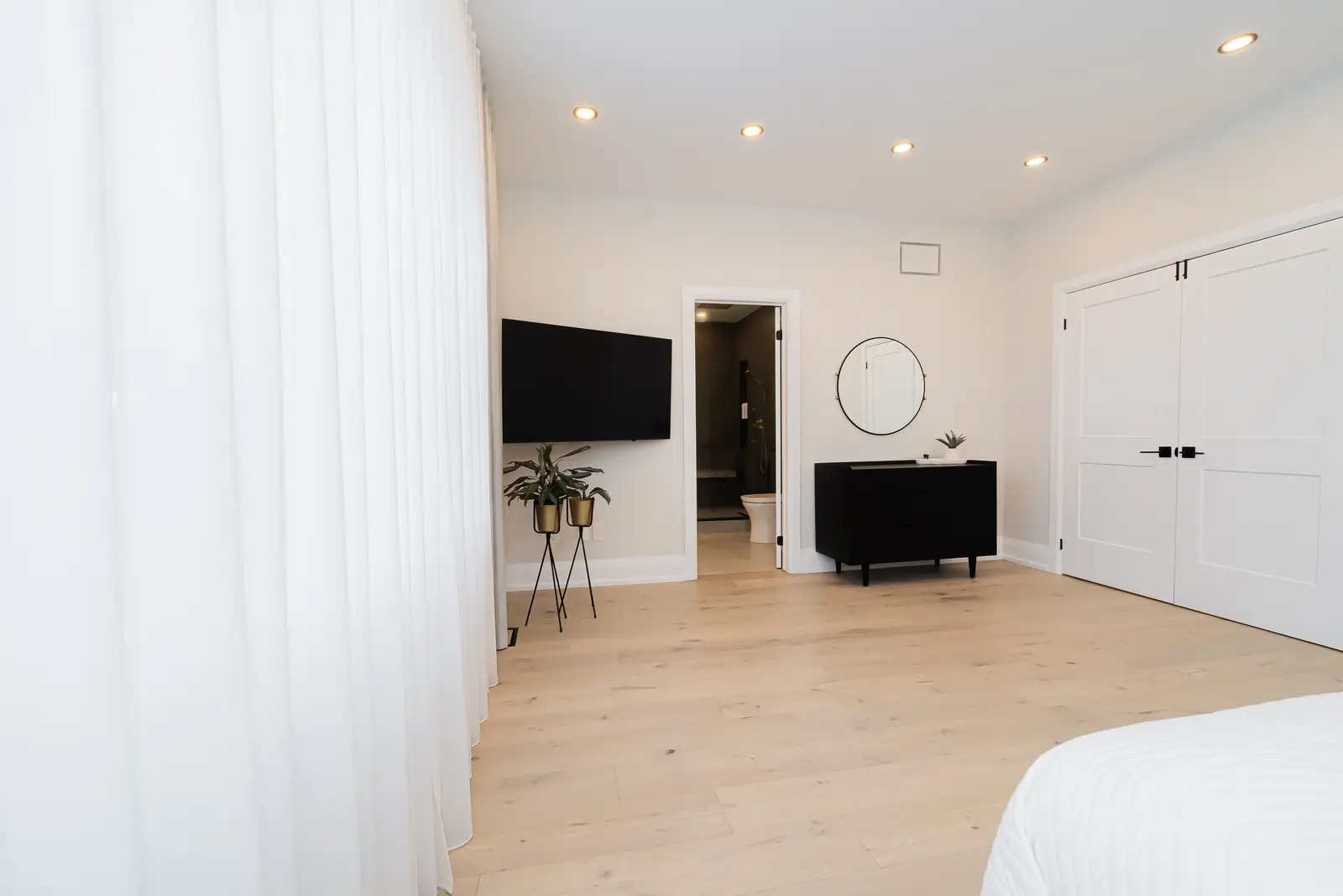 Interior of a Thornhill detached house renovation, with pale wood floors, black furnishings, and a walnut vanity in the primary bathroom.