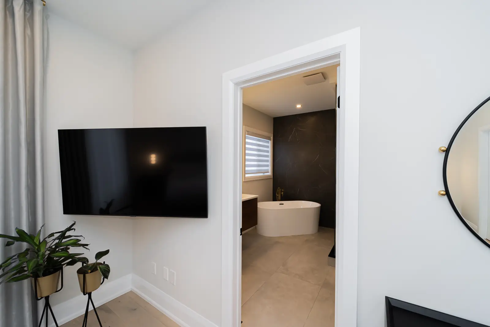 Interior of a Thornhill detached house renovation, with pale wood floors, black furnishings, and a walnut vanity in the primary bathroom.