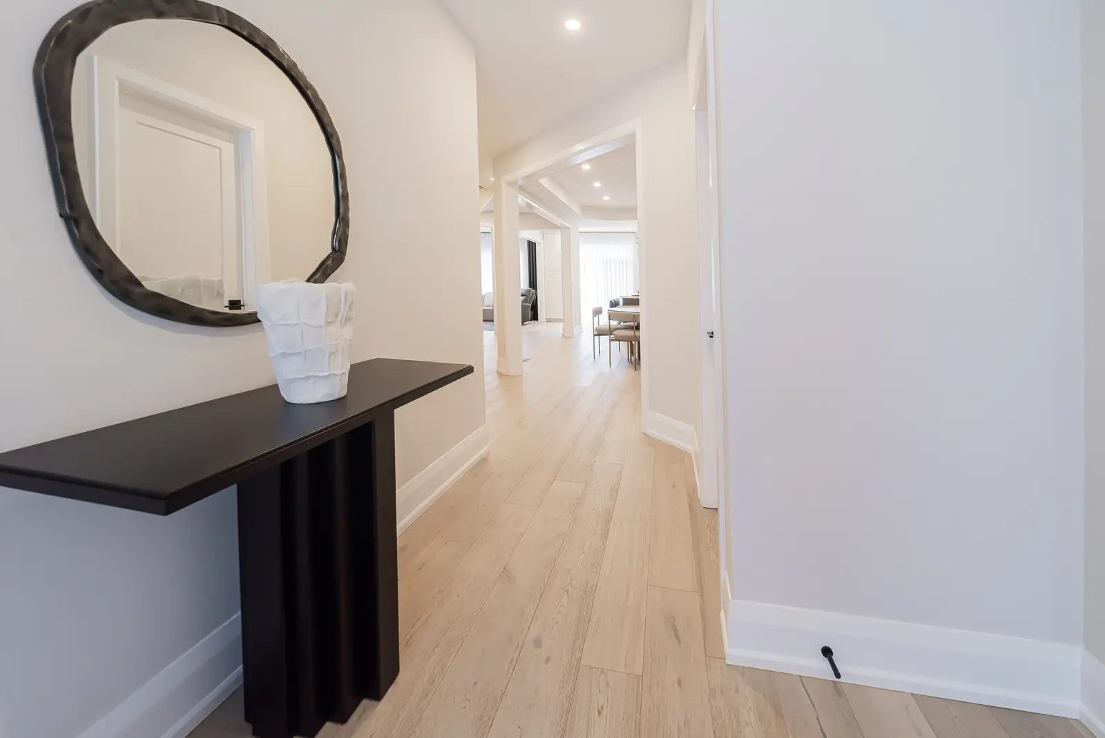 Interior of a Thornhill detached house renovation, with pale wood floors, black furnishings, and a walnut vanity in the primary bathroom.