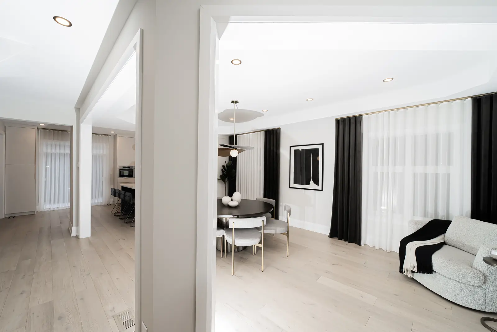 Interior of a Thornhill detached house renovation, with pale wood floors, black furnishings, and a walnut vanity in the primary bathroom.