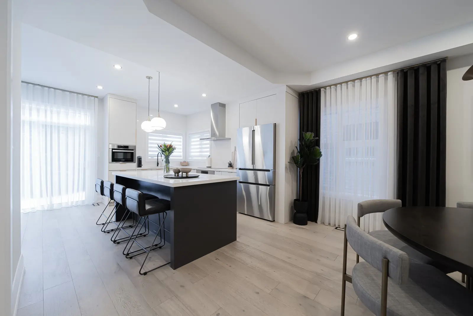 Interior of a Thornhill detached house renovation, with pale wood floors, black furnishings, and a walnut vanity in the primary bathroom.